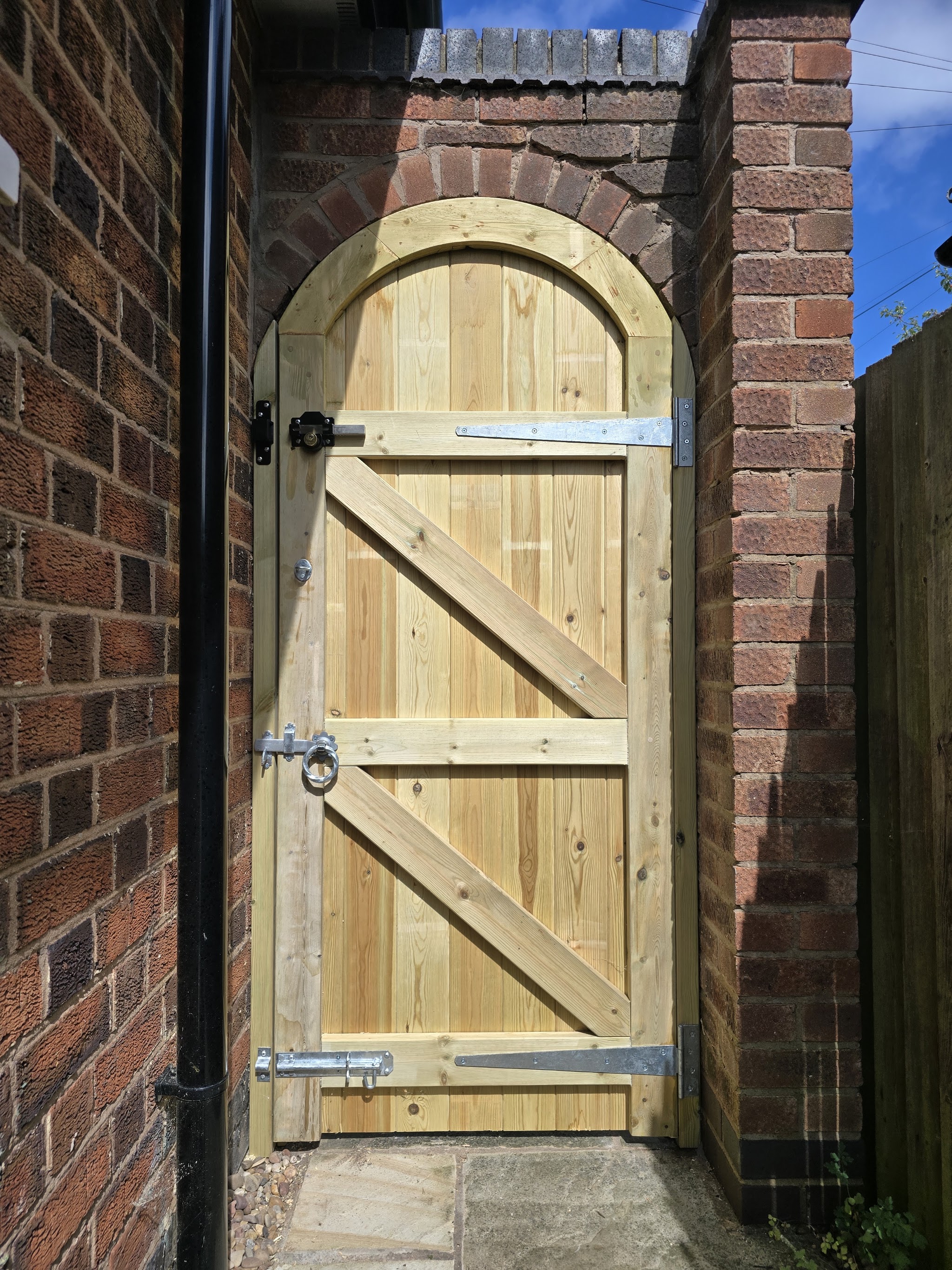 Arch-topped ledged and braced timber gate fitted in a brick archway