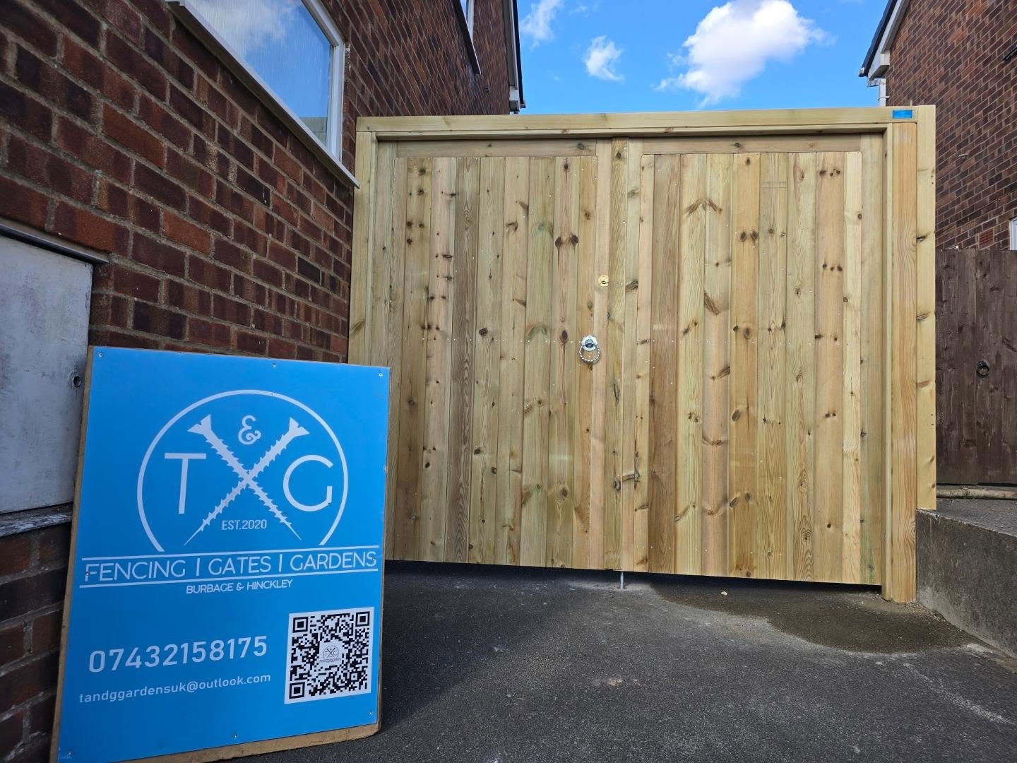Wide natural timber gate across the end of a driveway, with the T&G sign board